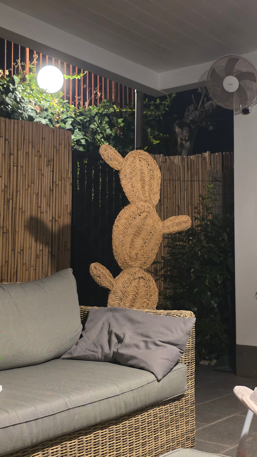 Area relax all'aperto del resort con divano in rattan, cactus intrecciato e ventilatore turbo